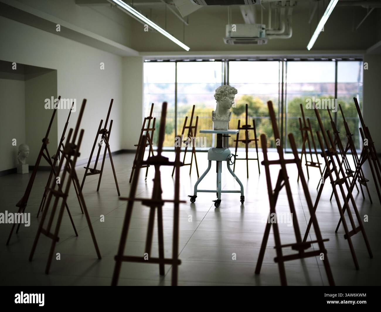 Gipsbüste auf Radsockel zwischen Holzpaffeleien im sonnendurchfluteten Art Studio an einem ruhigen Nachmittag Stockfoto