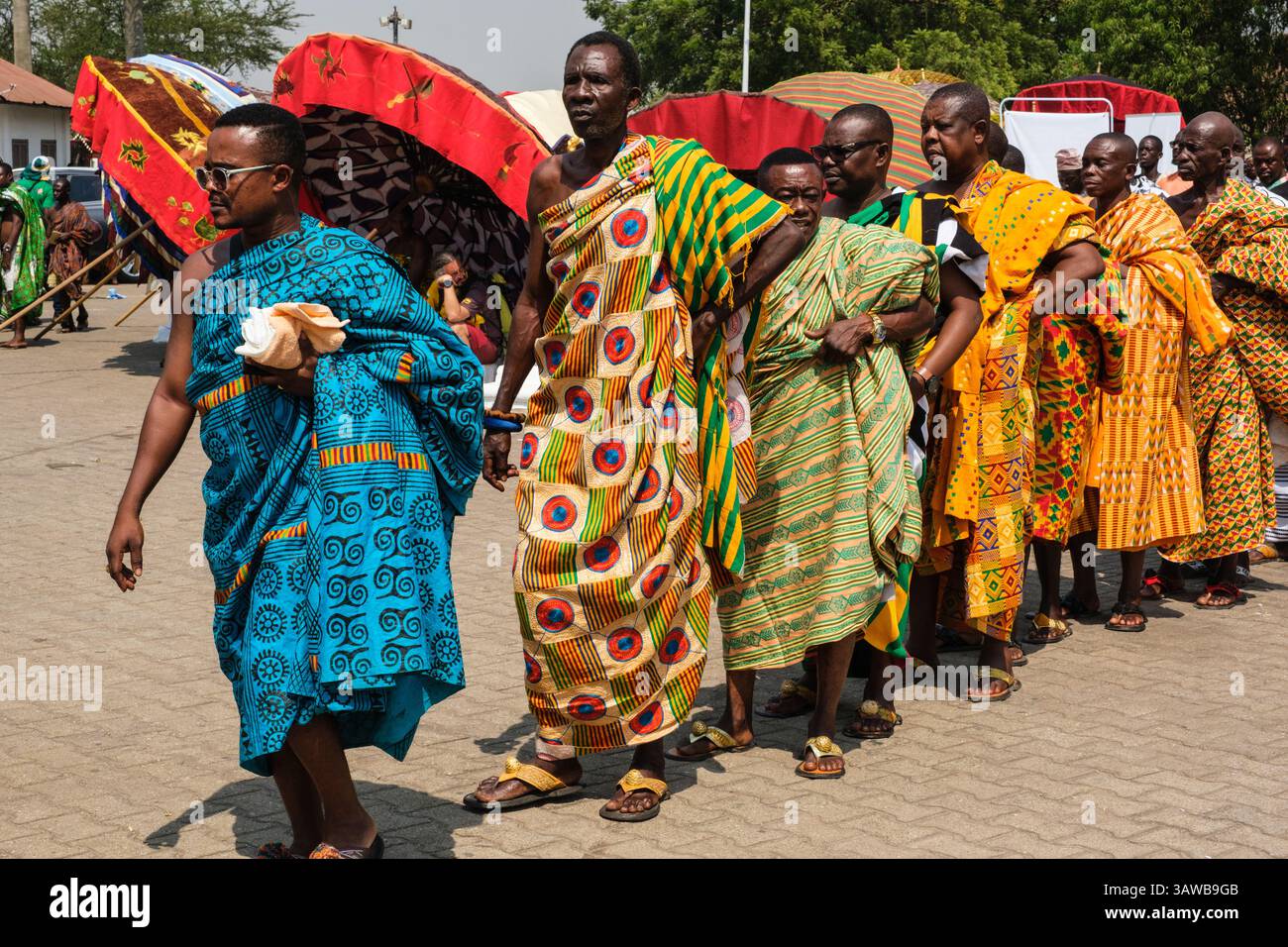 Kumasi, Ghana. Ashanti Akwasidae Zeremonie. Männer, einige tragen Kente Cloth, stellen sich auf, um den Zeremonienbereich zu betreten. Stockfoto