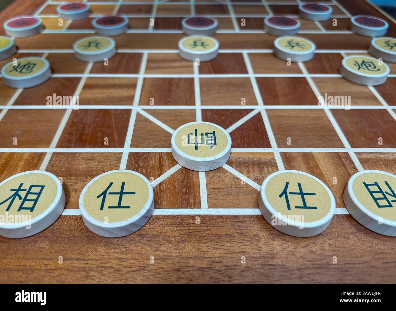 Ein traditionelles Xiangqi-Brettset (chinesisches Schachbrett) mit aufwändig gestalteten Holzstücken, die auf einem wunderschön gefertigten Brett angeordnet sind. Stockfoto