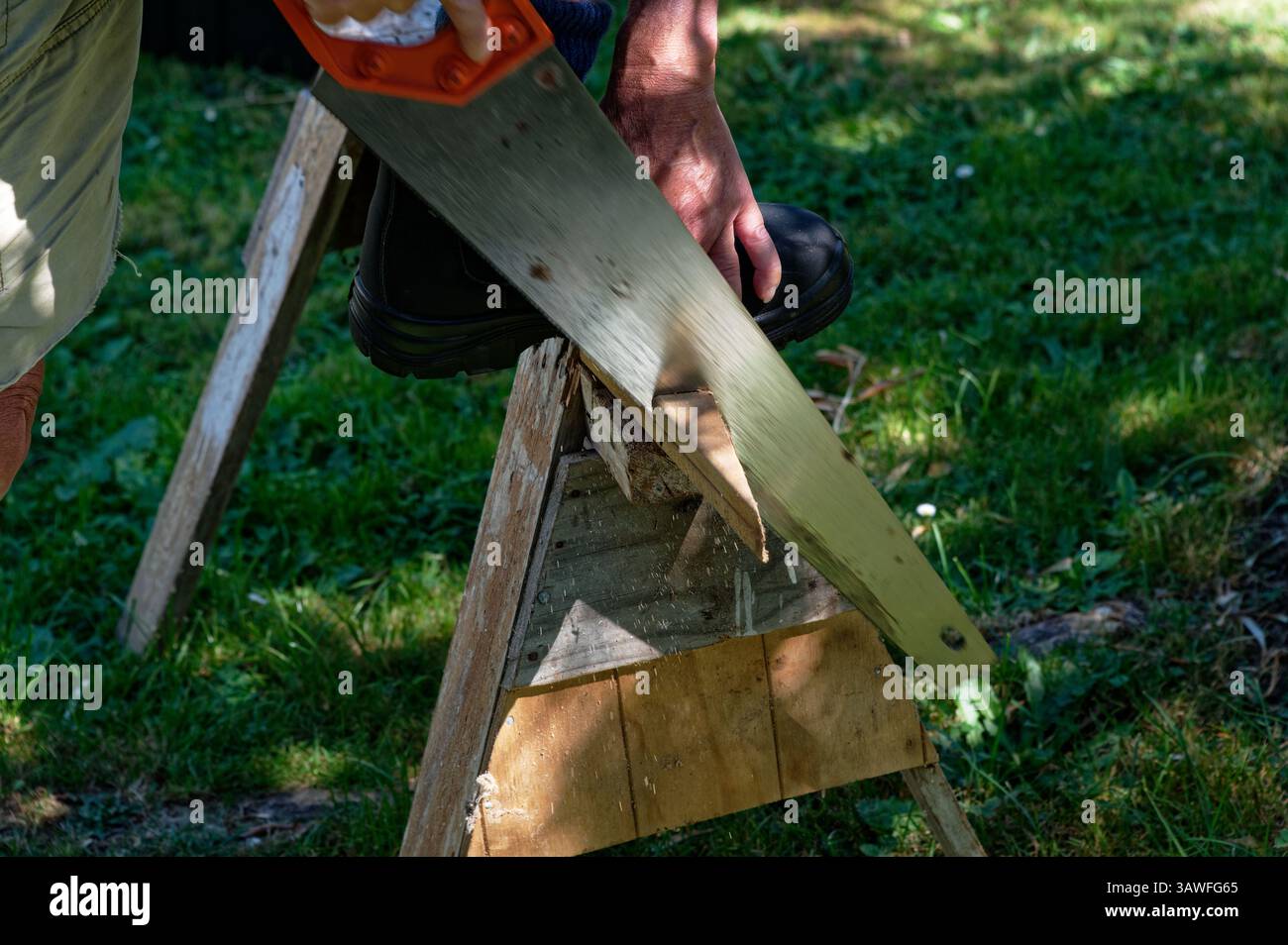 Ein Mann sägt ein Stück vom Ende eines Holzstücks ab Stockfoto