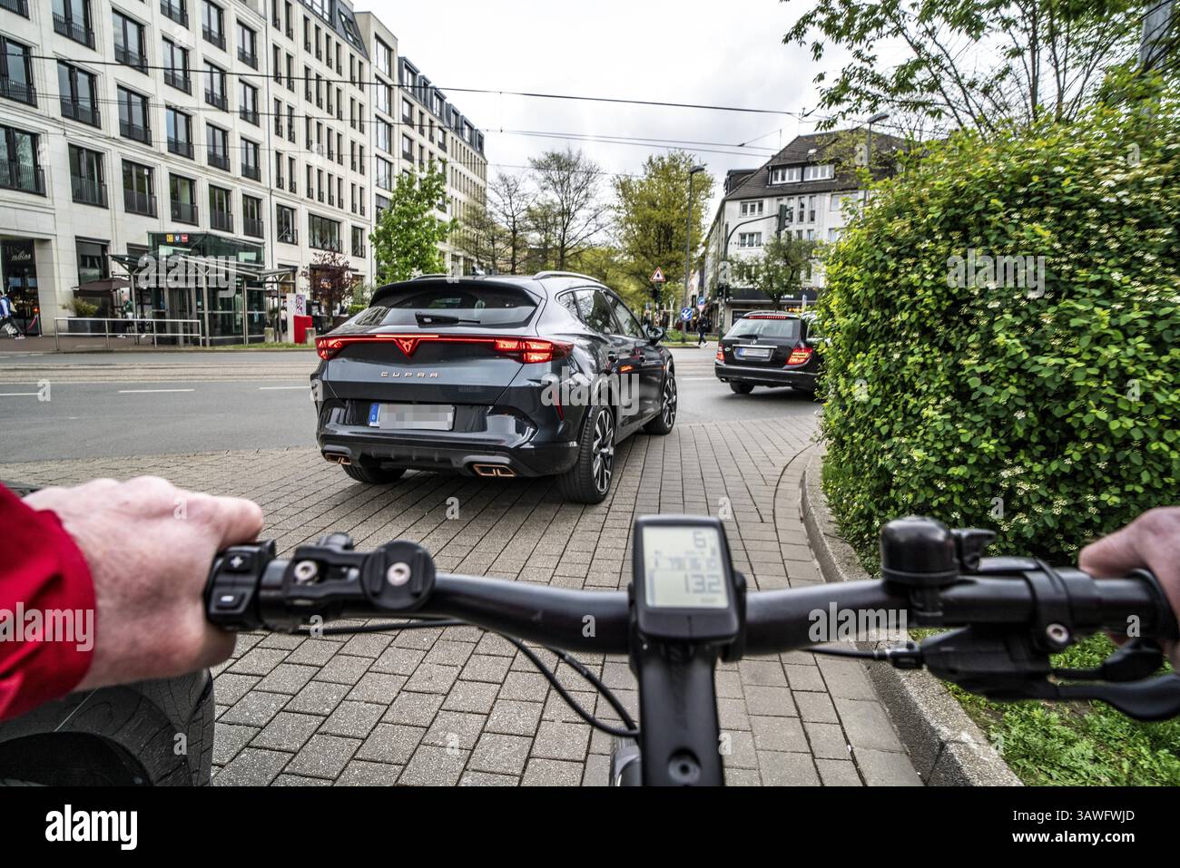 Radfahren in der Stadt, innerstädtische Straße, Radweg, Fahrräder haben Priorität, zweispuriger Verkehr mit geparkten Autos auf beiden Seiten, Radfahrerperspektive, es Stockfoto
