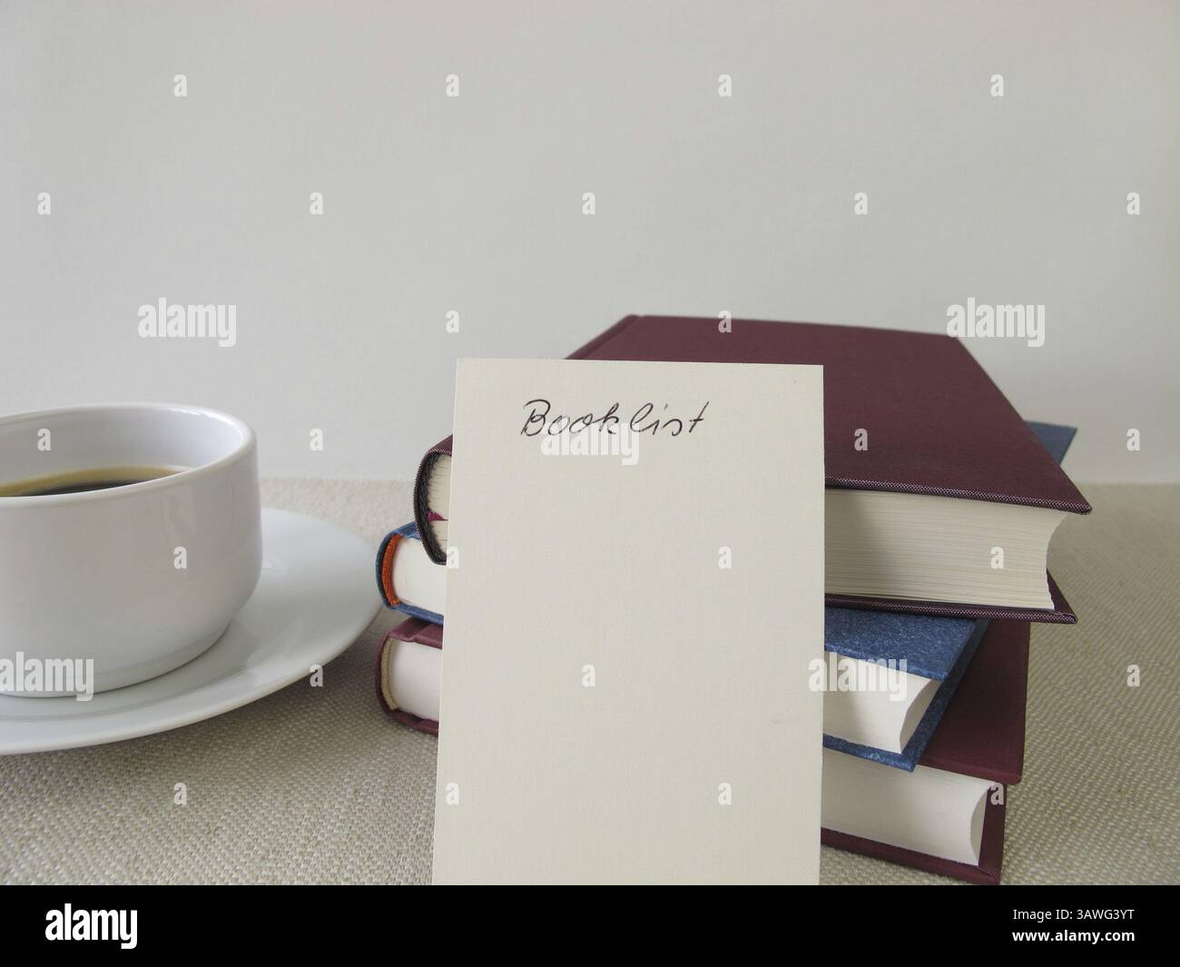 Ein Stapel Bücher, eine Liste mit Büchern und eine Tasse Stockfoto