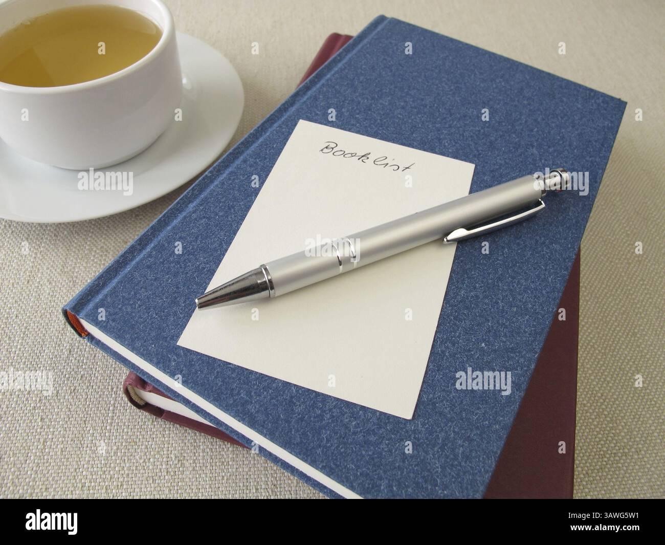 Ein Stapel Bücher, eine Liste mit Büchern und eine Tasse Tee Stockfoto