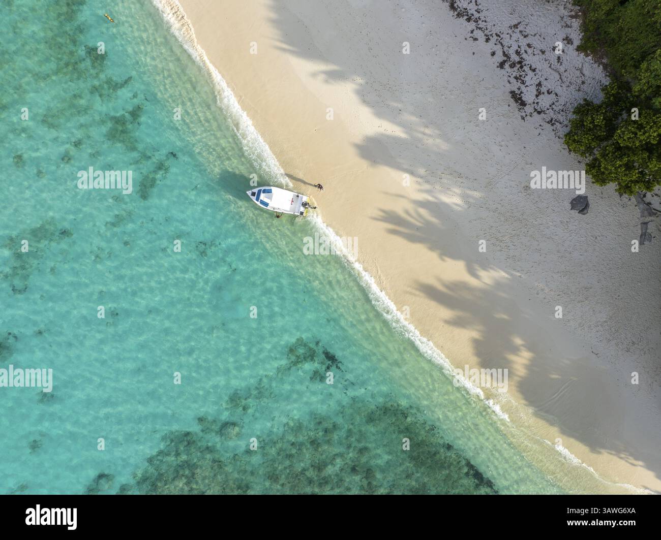Kleines Boot an einem abgeschiedenen Strand mit türkisfarbenem Wasser und sanften Wellen, Blick aus der Vogelperspektive, seychellen, Mahe, Port Glaud und Therese Island Stockfoto