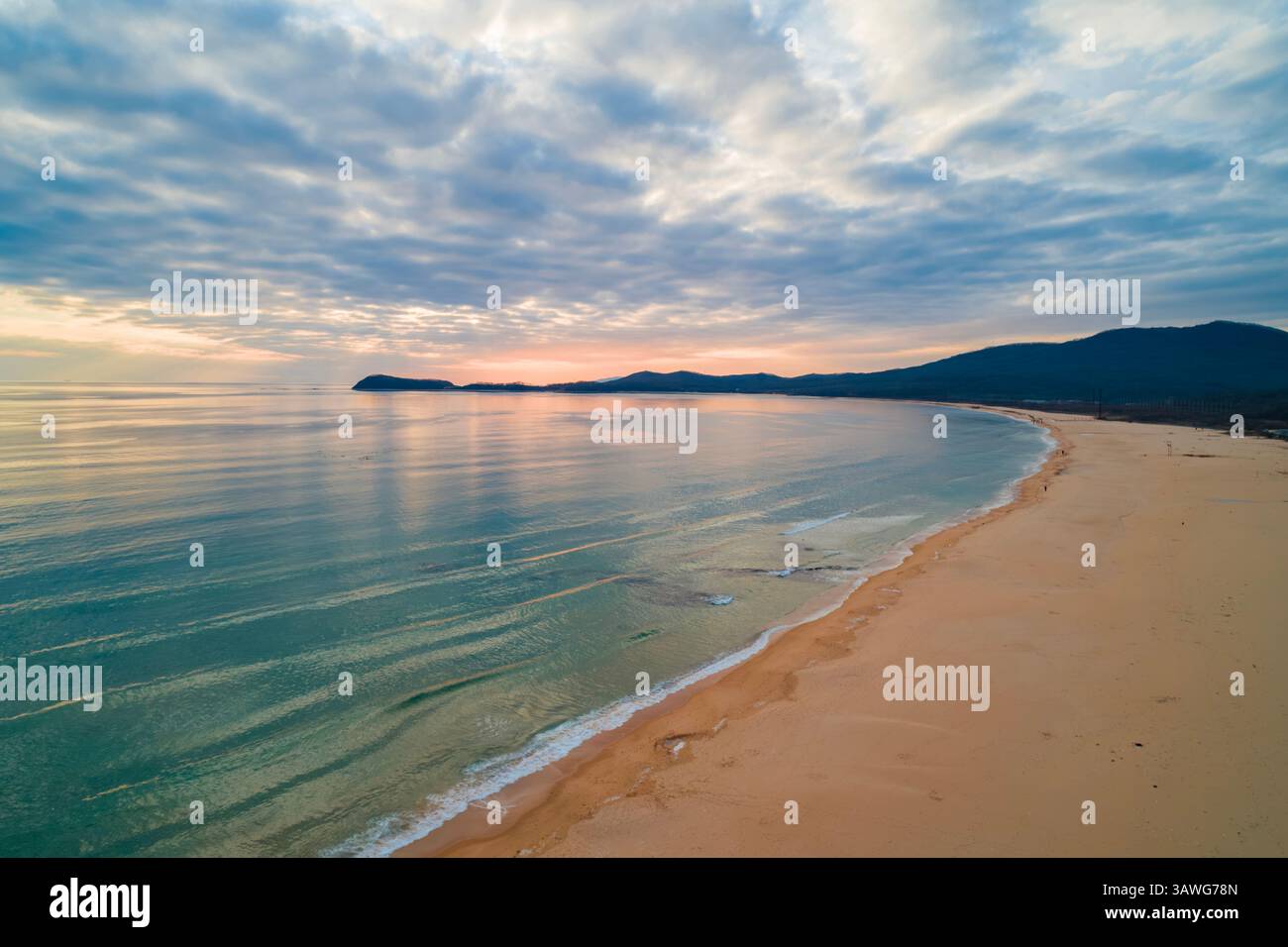 Wunderschöner Sonnenuntergang an der Küste mit sanften Wellen und einer ruhigen Landschaft, die am Abendhimmel festgehalten wird Stockfoto