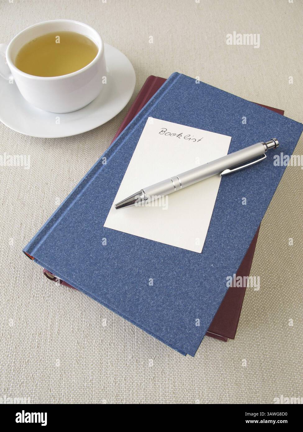Ein Stapel Bücher, eine Liste mit Büchern und eine Tasse Tee Stockfoto