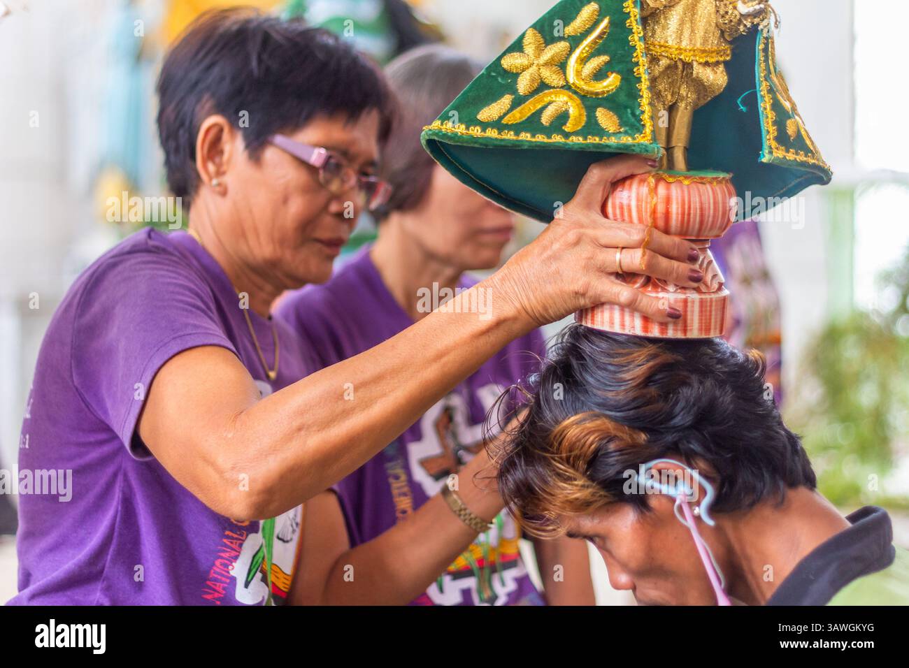 Ein Bild des Sto. Niño wird als Segen in der Ibajay Kirche in Aklan, Philippinen, während eines religiösen Rituals auf dem Kopf eines Gläubigen platziert Stockfoto