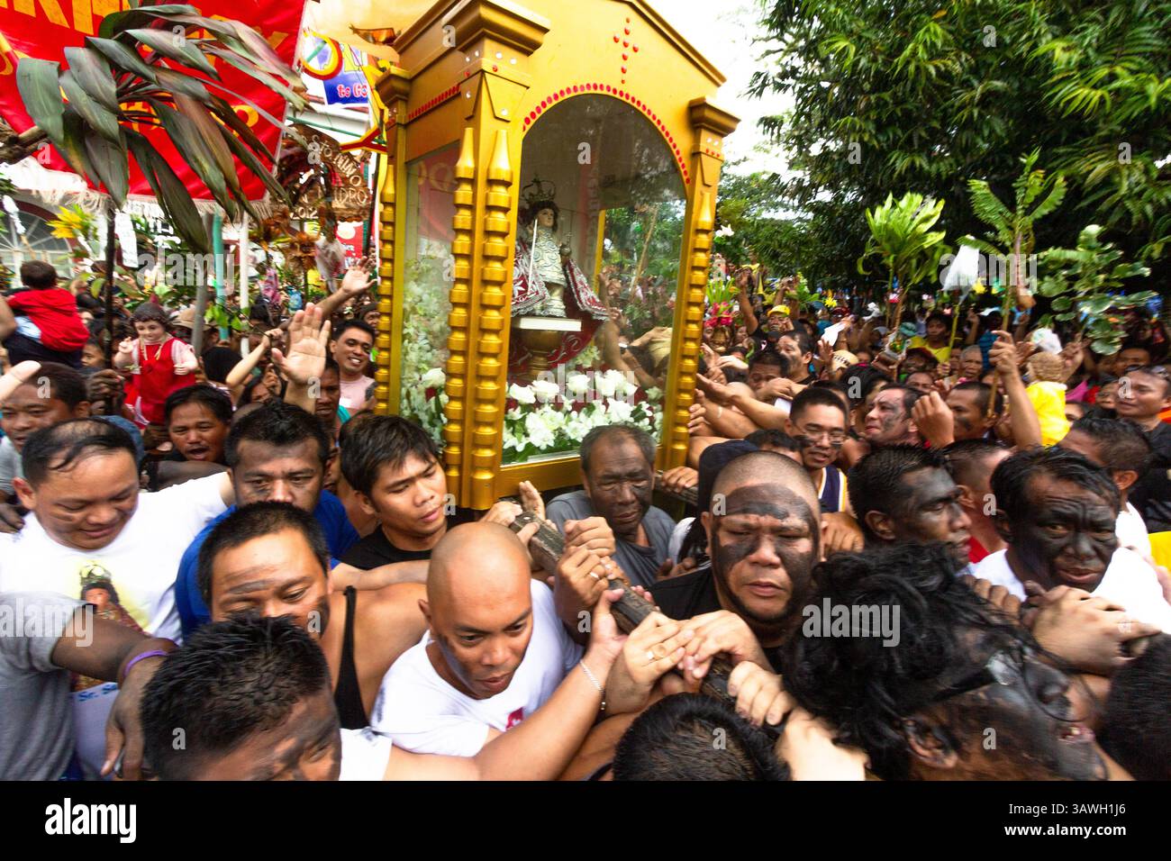 Während des Ibajay Ati-Ati Festivals in Aklan, Philippinen, tragen und verehren die Besucher ein Bild des Sto Niño auf ihren Schultern Stockfoto
