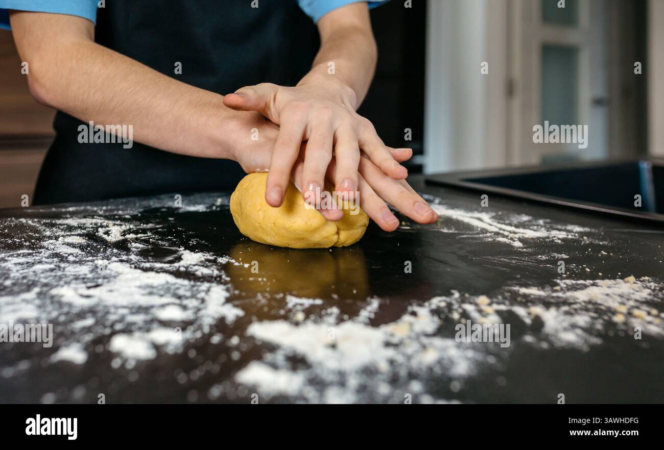 Nicht wiedererkennbarer Koch knete Teig auf bemehlter Küchentheke, der köstliche hausgemachte Pasta zubereitete Stockfoto