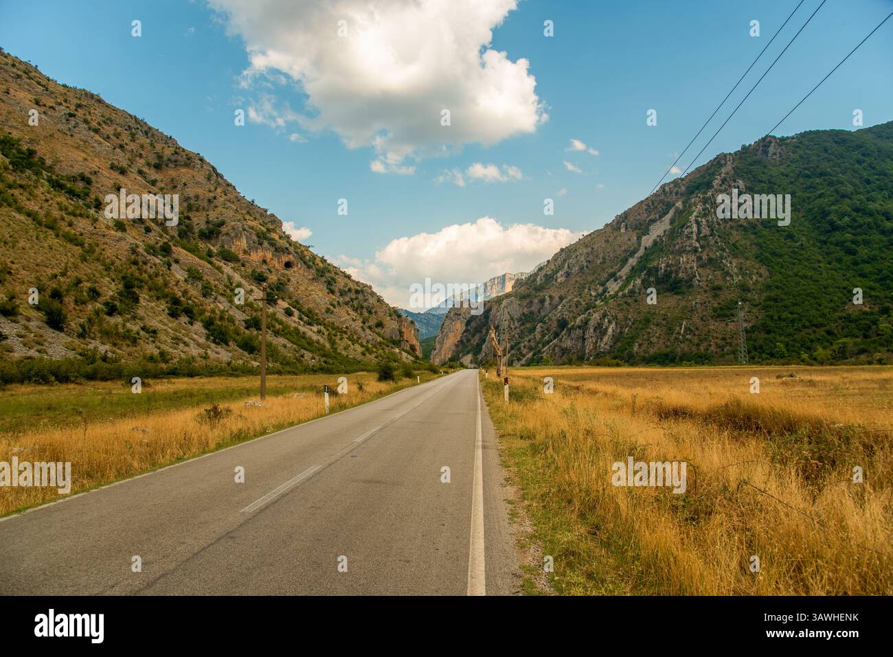 Die Rruga e Permetit (Permet Road) erstreckt sich über den Südwesten Albaniens, eingerahmt von riesigen Kalksteinkämmen und goldenen Wiesen unter einem weitläufigen Himmel Stockfoto