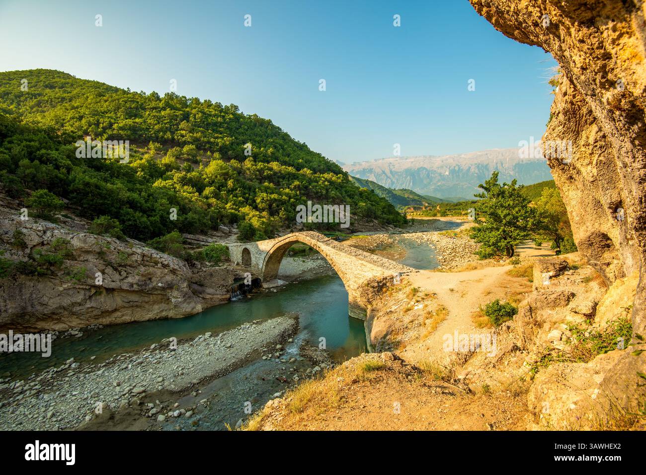 Der anmutige Bogen der Ura e Kadiut (Kadiu-Brücke) in Banje Permet durchquert Europas letzten wilden Fluss Vjosa, eingerahmt von zerklüfteten grünen Hängen Albaniens Stockfoto
