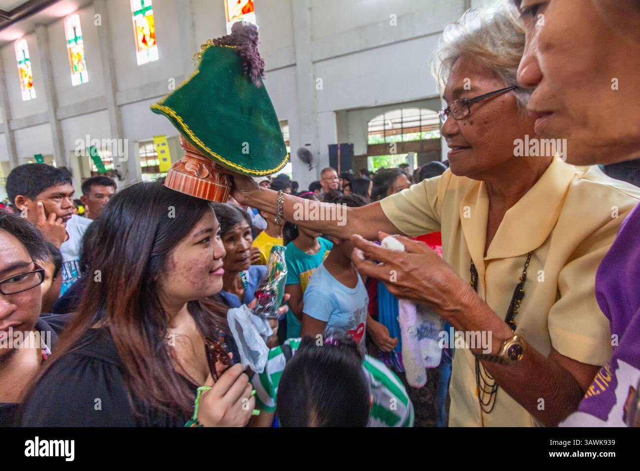 Ein Bild des Sto. Niño wird als Segen in der Ibajay Kirche in Aklan, Philippinen, während eines religiösen Rituals auf dem Kopf eines Gläubigen platziert Stockfoto