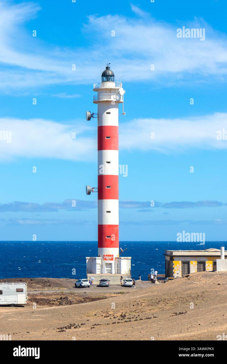 Ein rot-weiß gestreifter Leuchtturm steht an einer felsigen Küste mit blauem Himmel und Ozean im Hintergrund punta abona teneriffa kanarische Inseln spanien Stockfoto