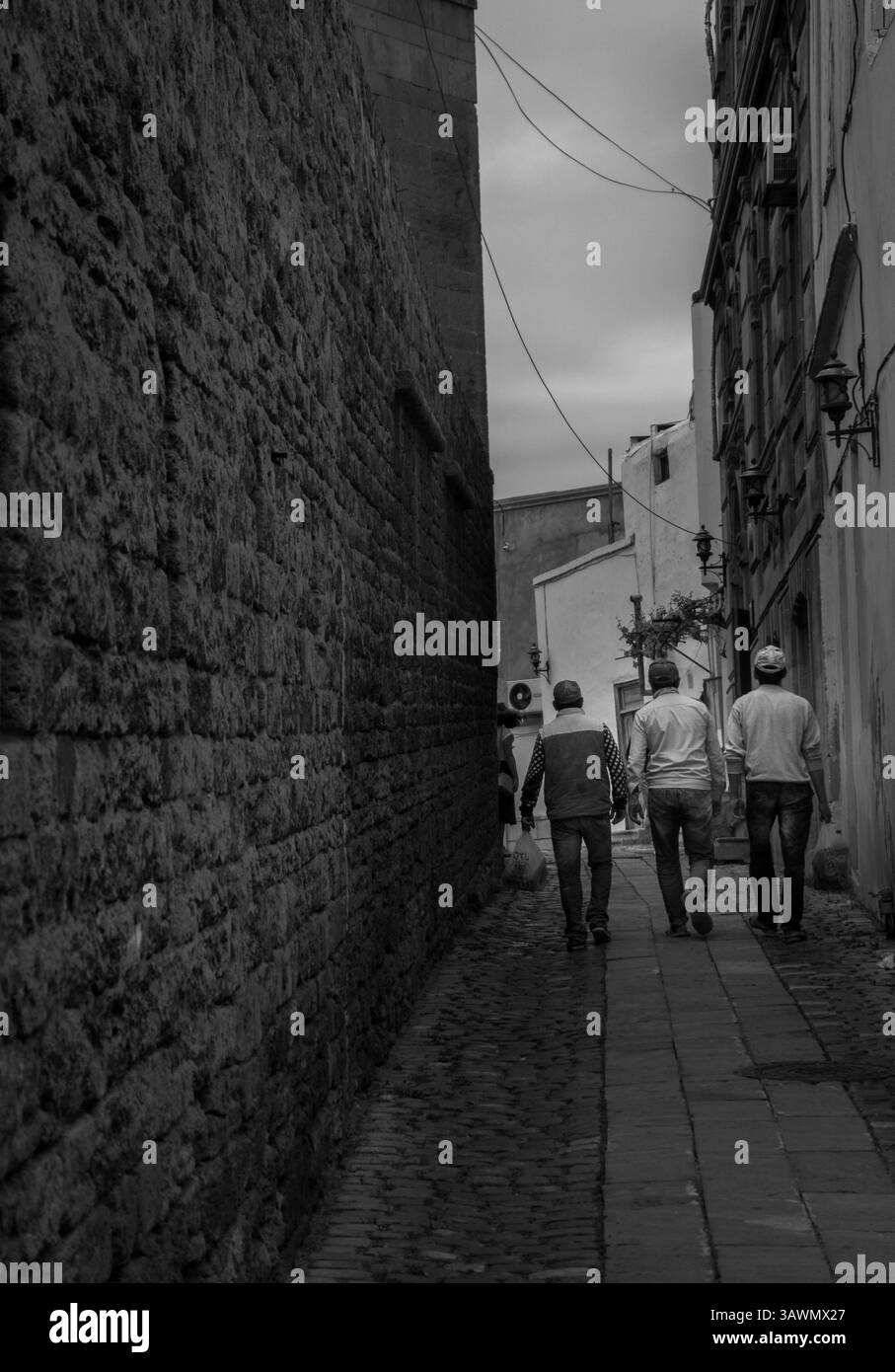 Drei Männer kommen müde von der Arbeit zurück nach Hause mit engen Straßen der Altstadt Stockfoto
