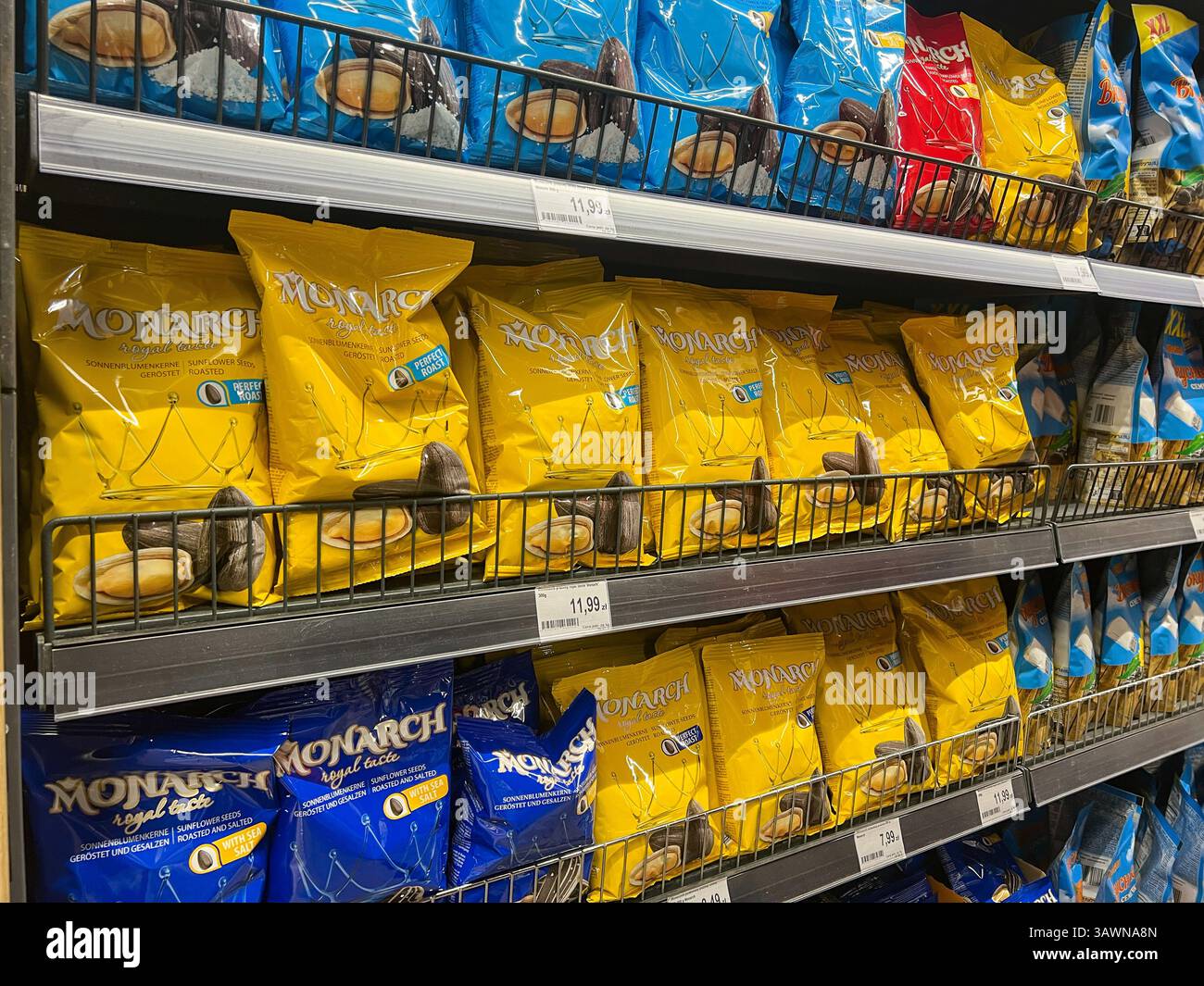 Posen, Polen - 18. April 2025: Leuchtend farbige gelbe und blaue Beutel mit Monarch gerösteten Sonnenblumensamen werden ordentlich in den Regalen des Lebensmittelgeschäfts ausgestellt Stockfoto