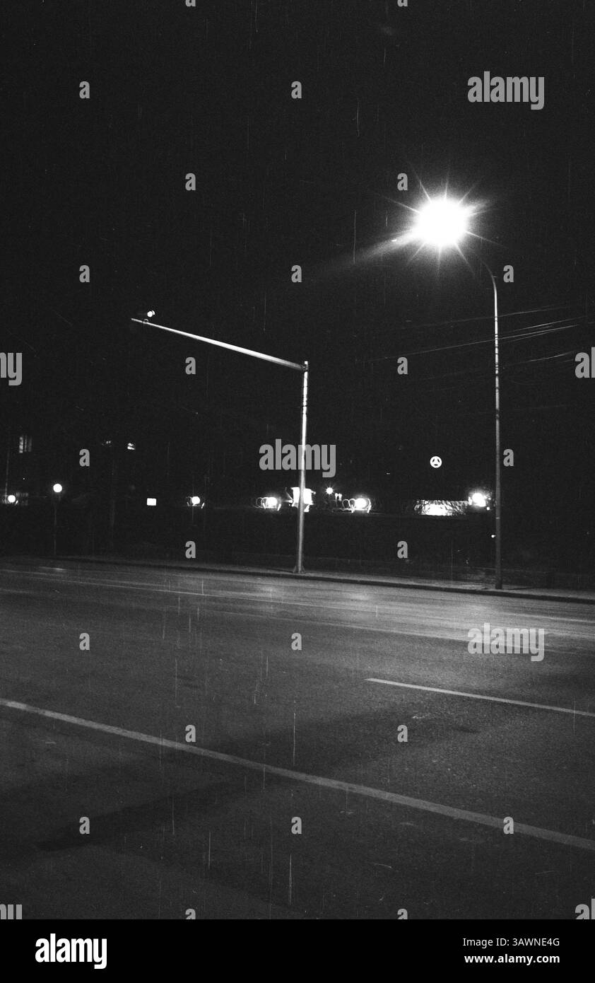 Von einer glühenden Lampe beleuchtete Straße unter dem ruhigen Nachthimmel in der Nähe einer belebten Stadt : Mercedes‑Benz Showroom auf der Pekinger Nachtstraße - Vintage Film Photography, 2010er Jahre, Peking, China Stockfoto