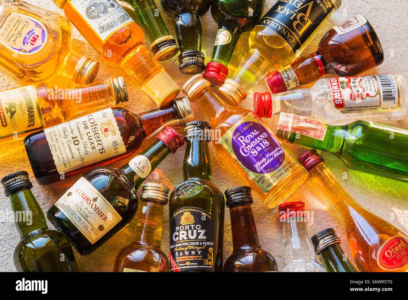 Miniaturflaschen mit Vodka, Whiskey, Scotch, Cognac, Brandy, Porto auf strukturiertem Hintergrund. Stockfoto
