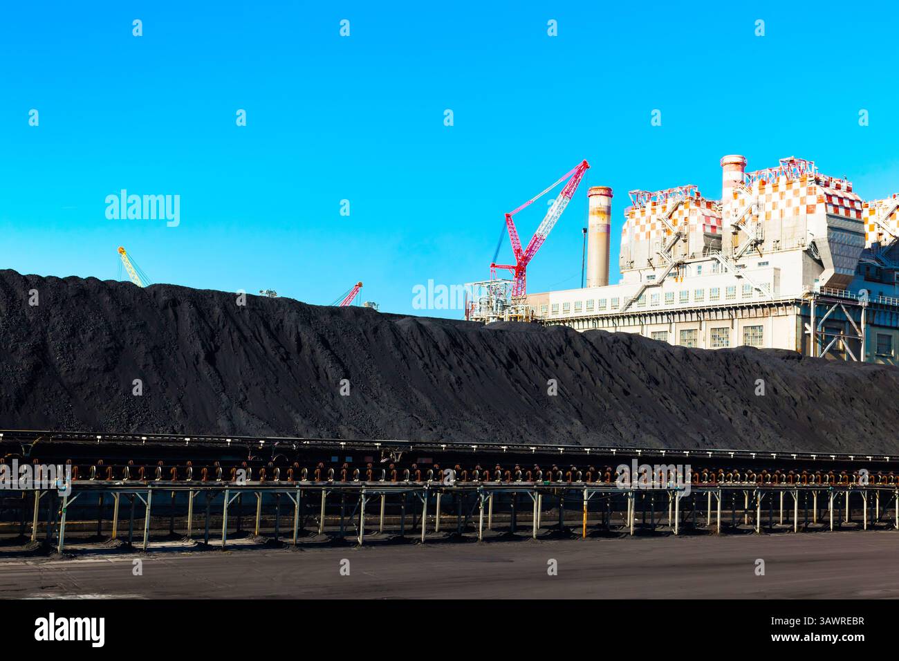 Kohleverarbeitungsanlage mit Rohren, einem Kran und einem Kohlehaufen. Stockfoto