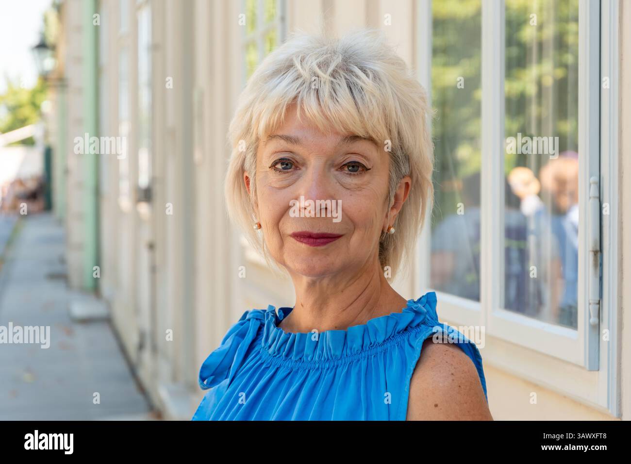 Porträt einer lächelnden Frau mittleren Alters mit kurzen Haaren und Make-up im Freien Stockfoto