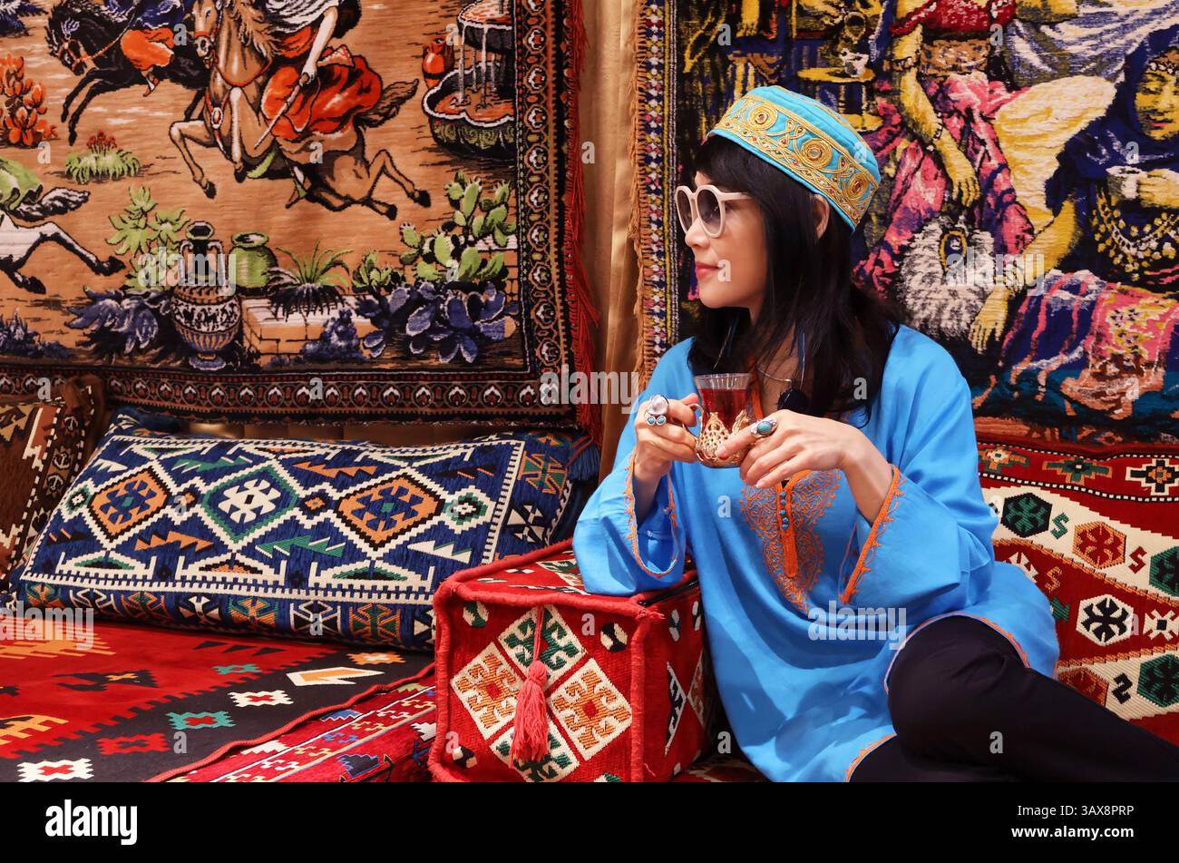 Frau hält ein Glas heißen türkischen Kräutertees in einem Tulpenglas Stockfoto