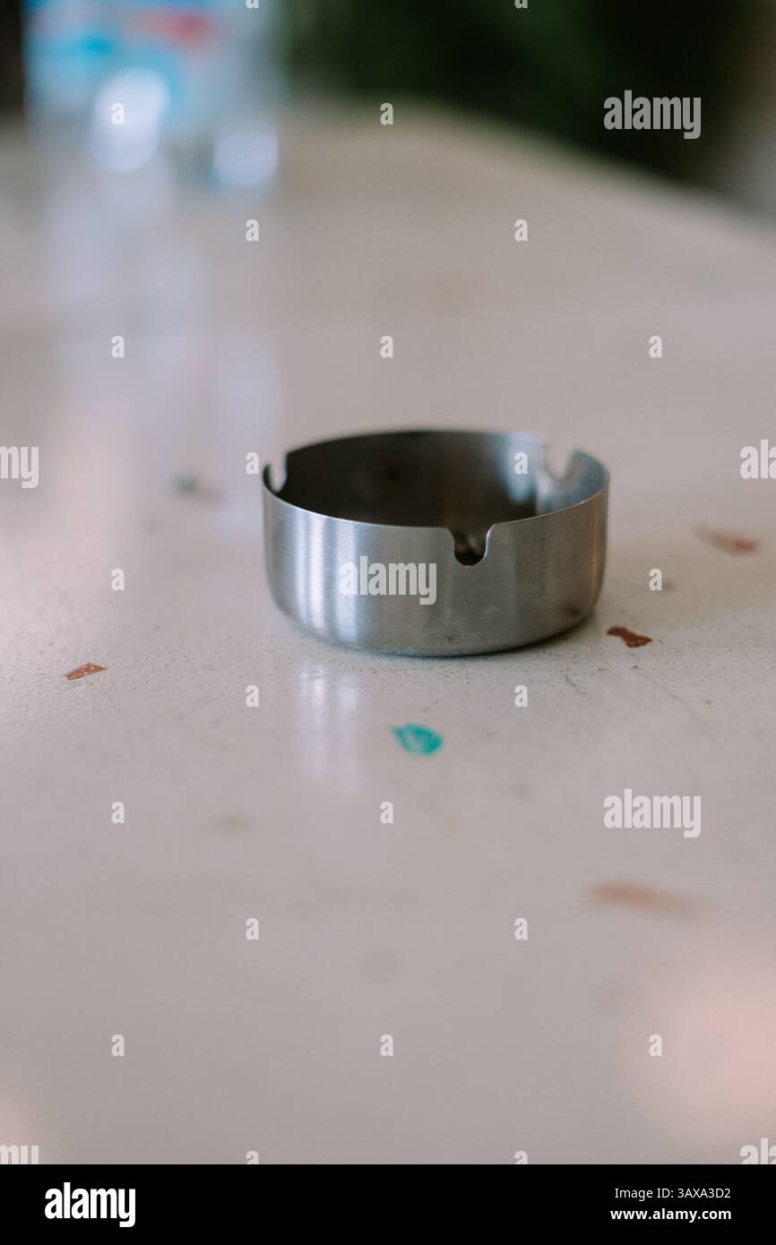 Nahaufnahme eines einfachen Aschenbechers aus Edelstahl auf einer gepunkteten Arbeitsplatte, innen geschossen. Stockfoto