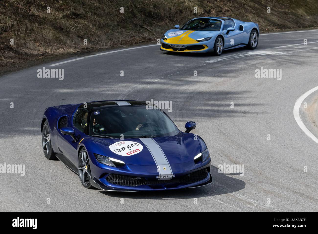 Le Valtin, Frankreich - Blick auf einen blauen Ferrari 296 GTS Assetto Fiorano und einen weiteren Ferrari, der auf einer Straße fährt. Stockfoto
