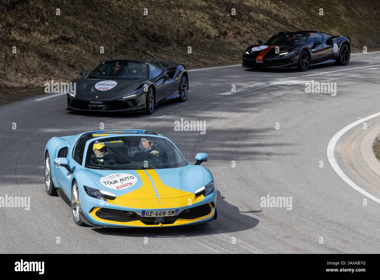 Le Valtin, Frankreich - Blick auf einen blau-gelben Ferrari 296 GTS Assetto Fiorano und zwei weitere Ferrari, die auf einer Straße fahren. Stockfoto