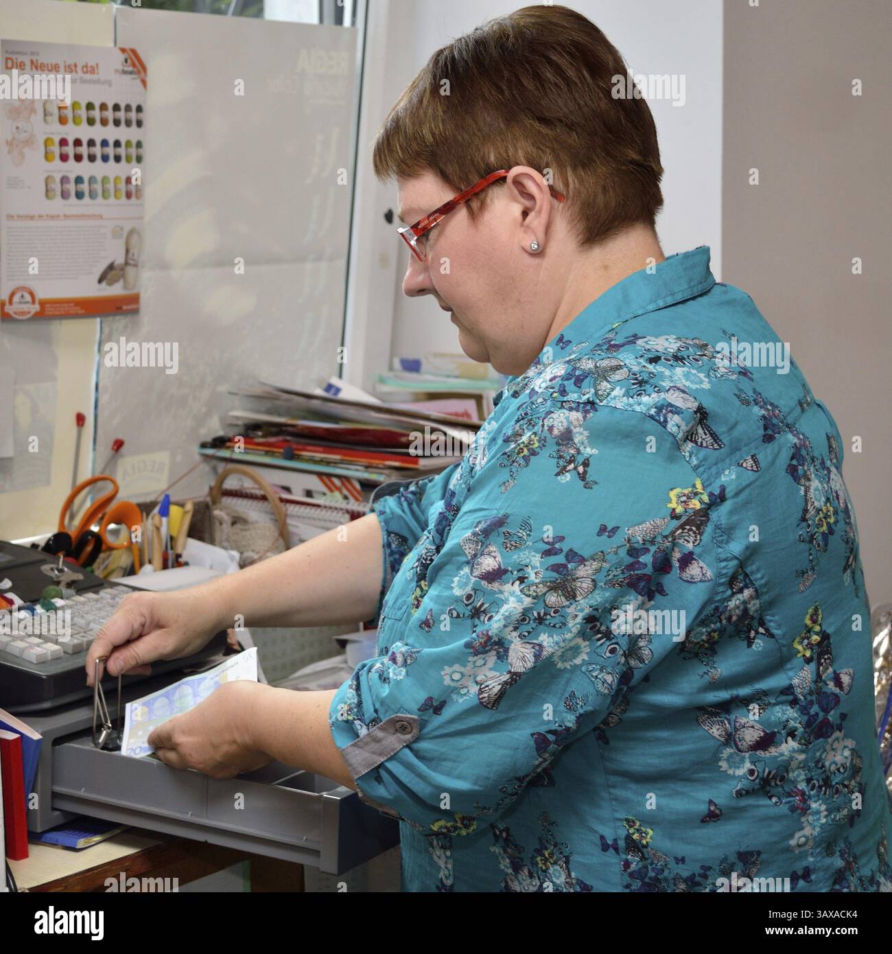 Die Verkäuferin bringt Geld in die Kasse Stockfoto