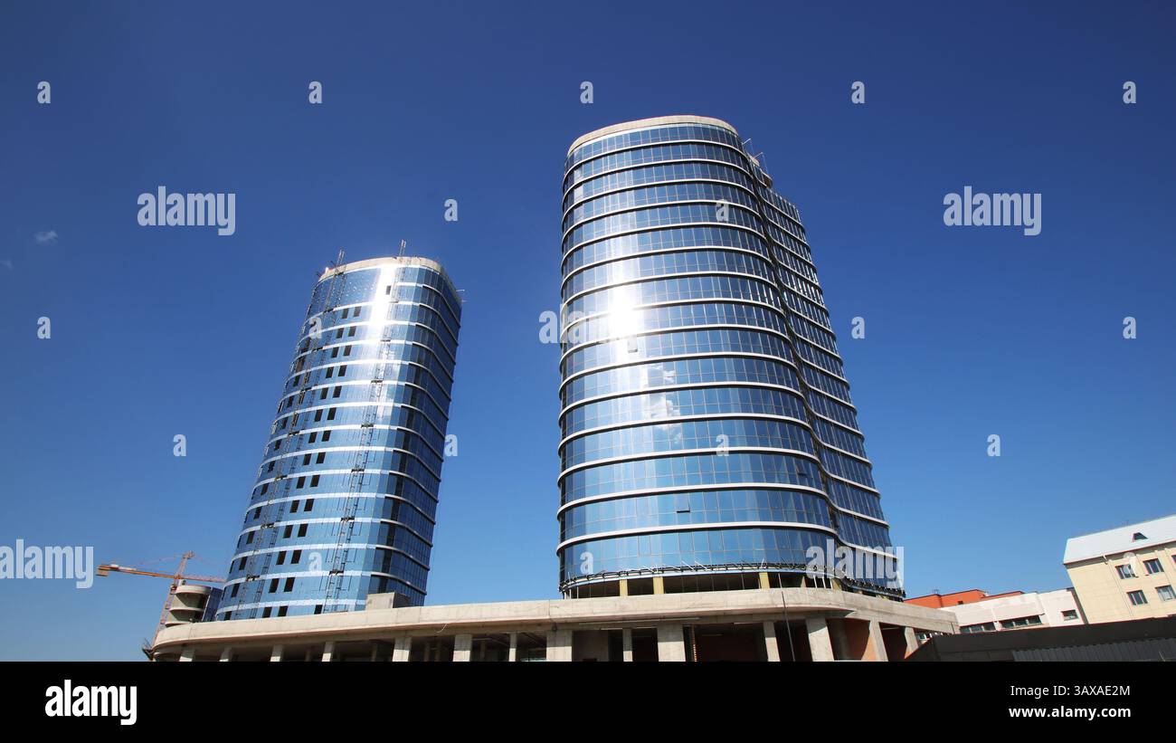Es gibt zwei extrem hohe Gebäude, die hervorstehend stehen und vor einem wunderschönen blauen Himmel stehen, der ihre beeindruckende Größe unterstreicht Stockfoto