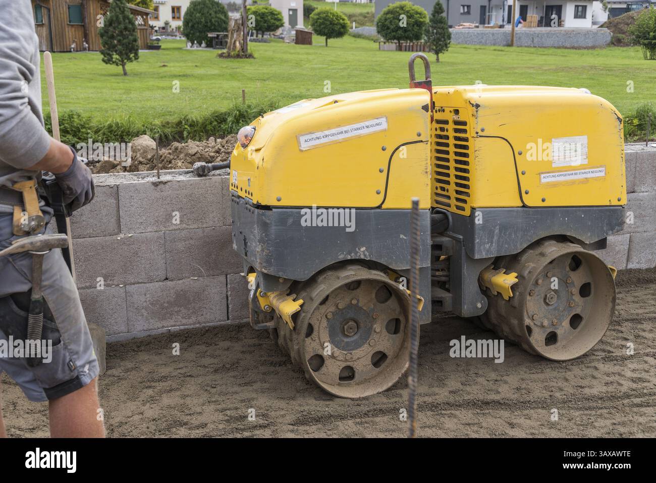 Baustellenarbeiten mit Grabenwalze zur Verdichtung des Bodens als Grundlage für den Hausbau Stockfoto