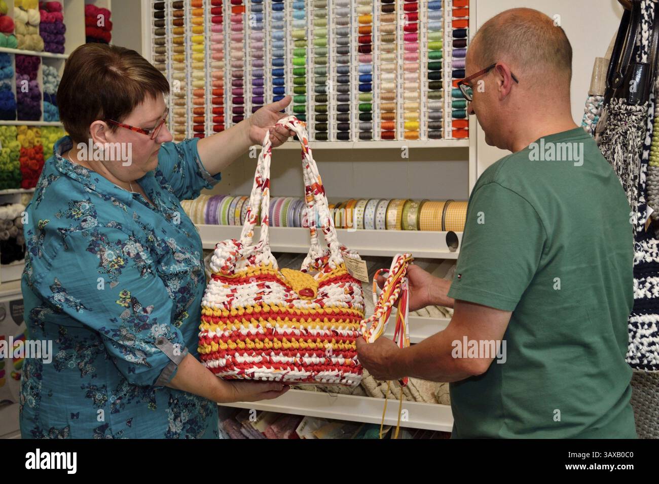 Textil Verkäuferin zeigt Kunden Handtasche Stockfoto
