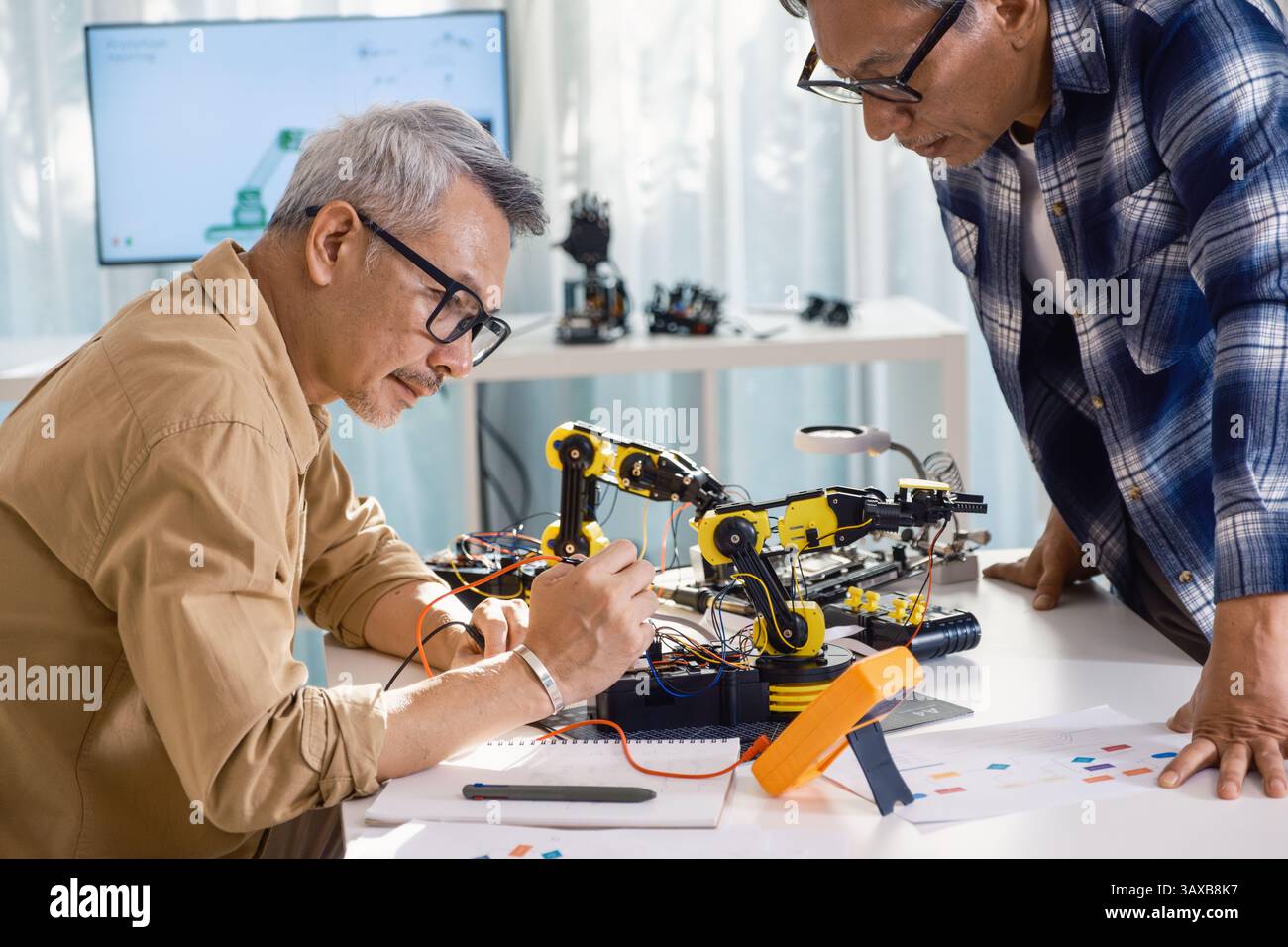 asiatischer Senior Engineer Programmierroboterarm im Labor für Automatisierungs- und Elektroniktechnologie Stockfoto