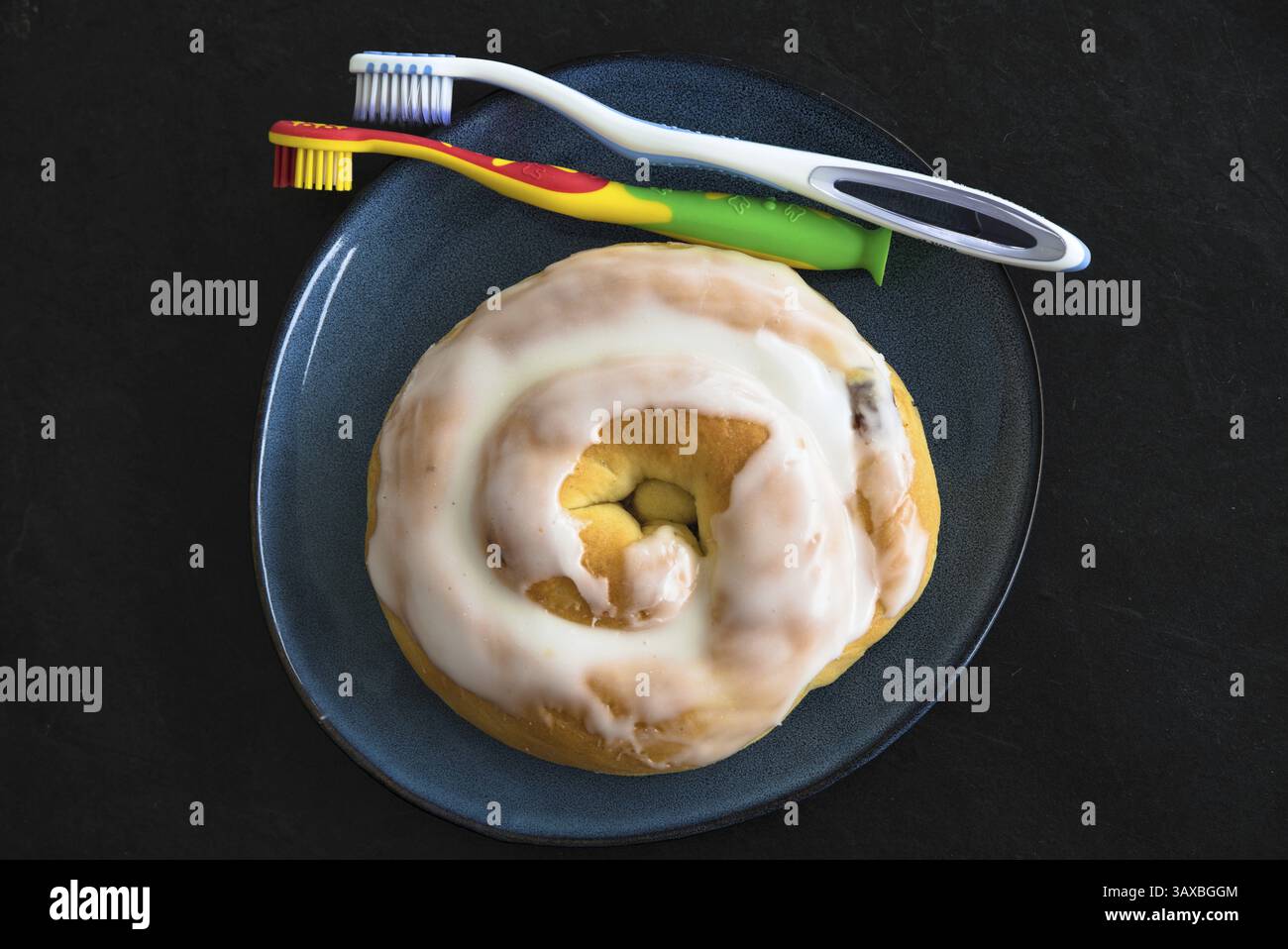 Zahnbürste und Dessert mit Glasur auf dem Teller - Karies-Risiko durch falsche und ungesunde Essgewohnheiten Stockfoto