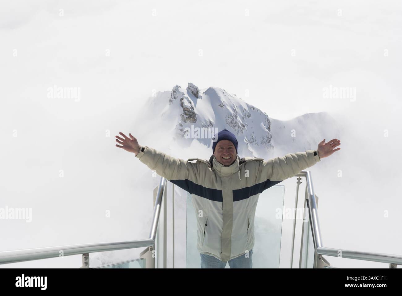Der Mann steht fröhlich auf der Treppe ins Nirgendwo auf dem Dachstein Stockfoto
