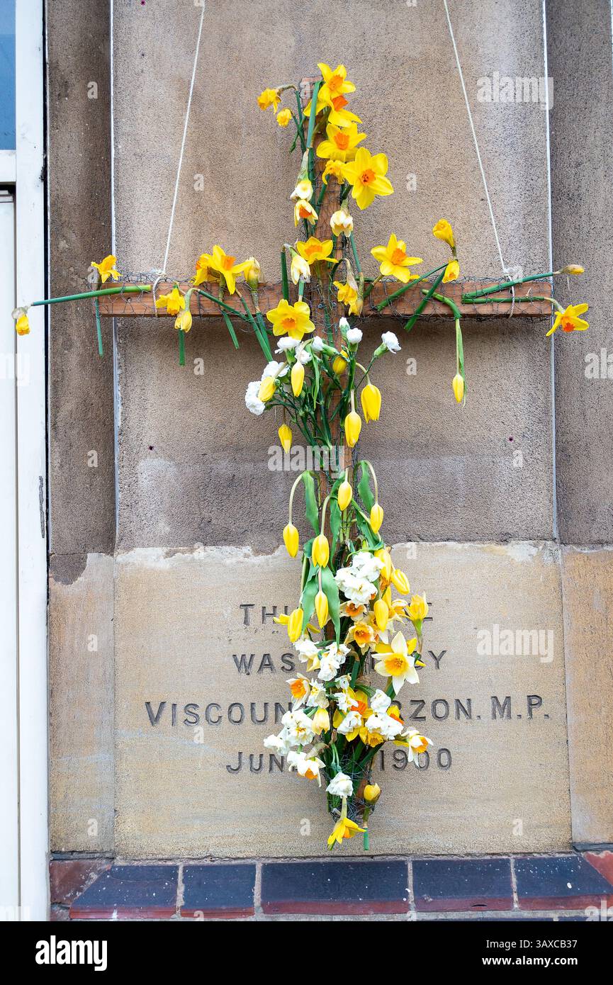Slough, Großbritannien. April 2025. Ein Kruzifix mit Narzissen und Tulpen vor einer Kirche in Slough, Berkshire nach Gottesdiensten am Ostersonntag. Heute wurde bekannt gegeben, dass Papst Franziskus leider verstorben ist. Quelle: Maureen McLean/Alamy Live News Stockfoto