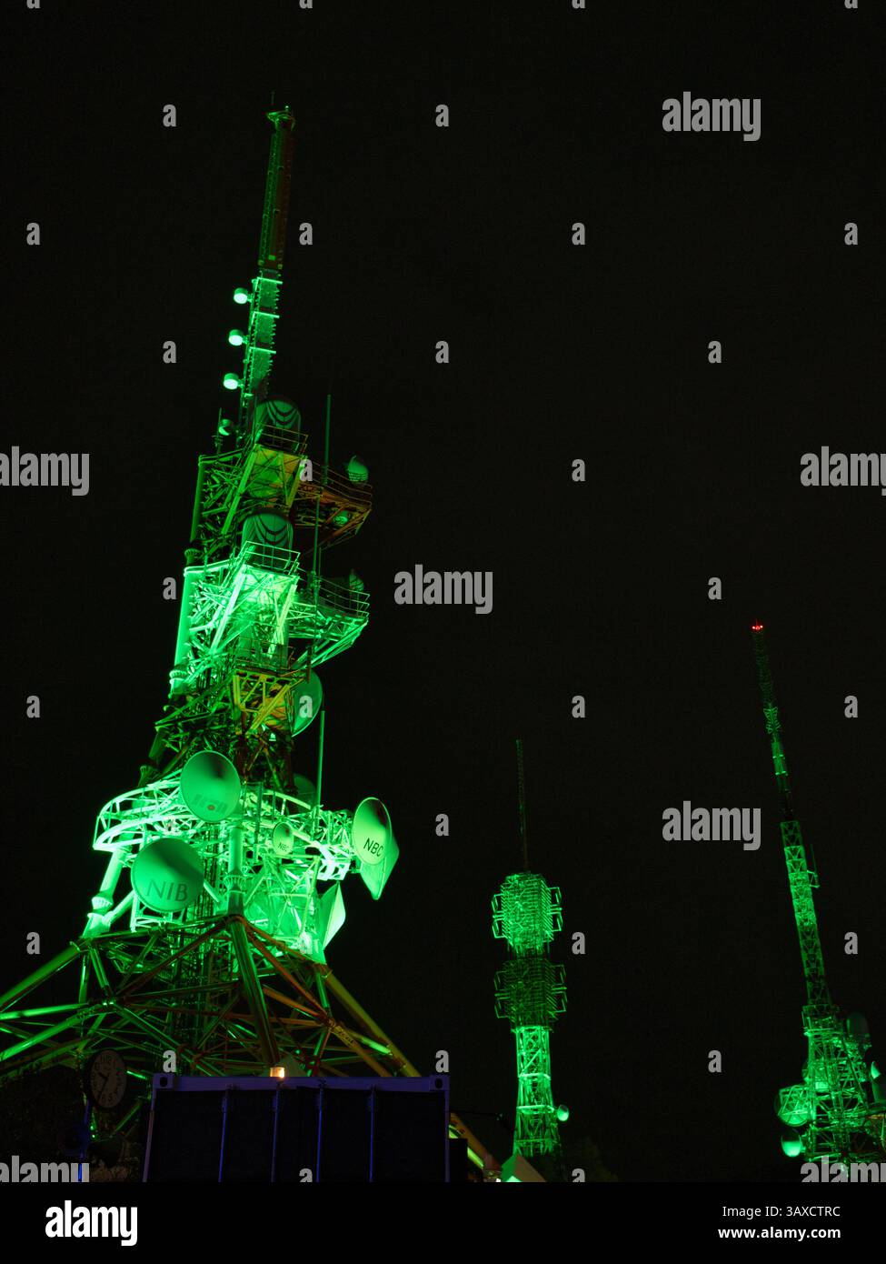 Beleuchtete Kommunikationstürme auf dem Berg Inasa, Nagasaki, Kyushu, Japan bei Nacht. Die grünen Lichter heben die komplizierten Strukturen vor einem dunklen SK hervor Stockfoto