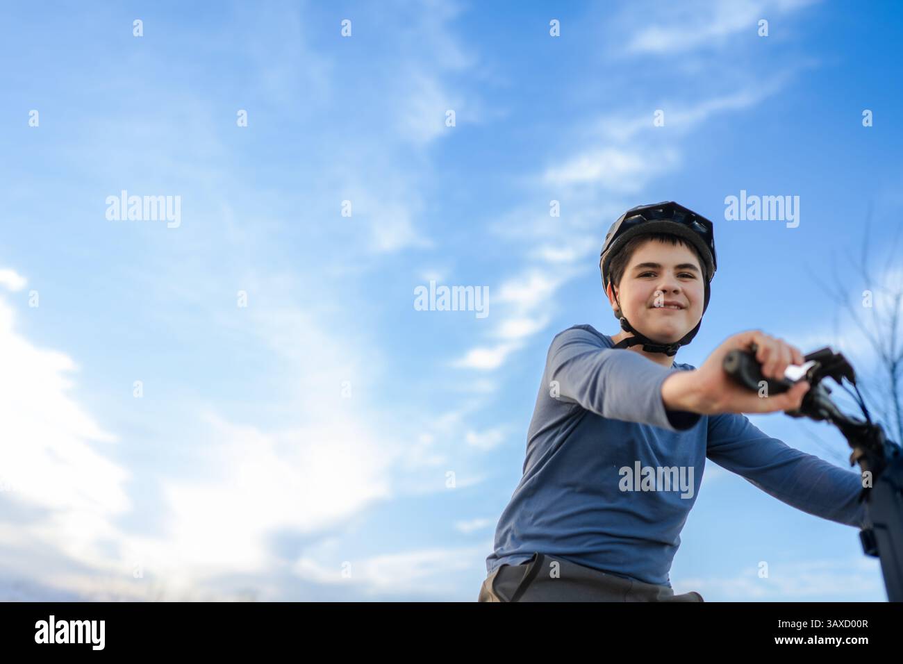Tween Boy trägt Helm auf dem Fahrrad vor blauem Himmel Stockfoto
