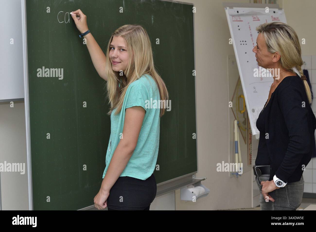 Die Lehrerin erzählt dem Schüler ein englisches Wort, das sie auf die Tafel schreibt Stockfoto