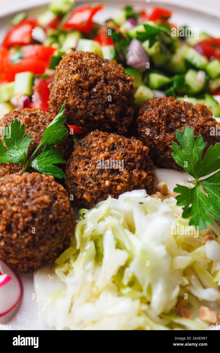 Falafel: Kichererbsenbällchen auf einem Teller mit Tahini, Gemüsesalat und Krautsalat. Stockfoto
