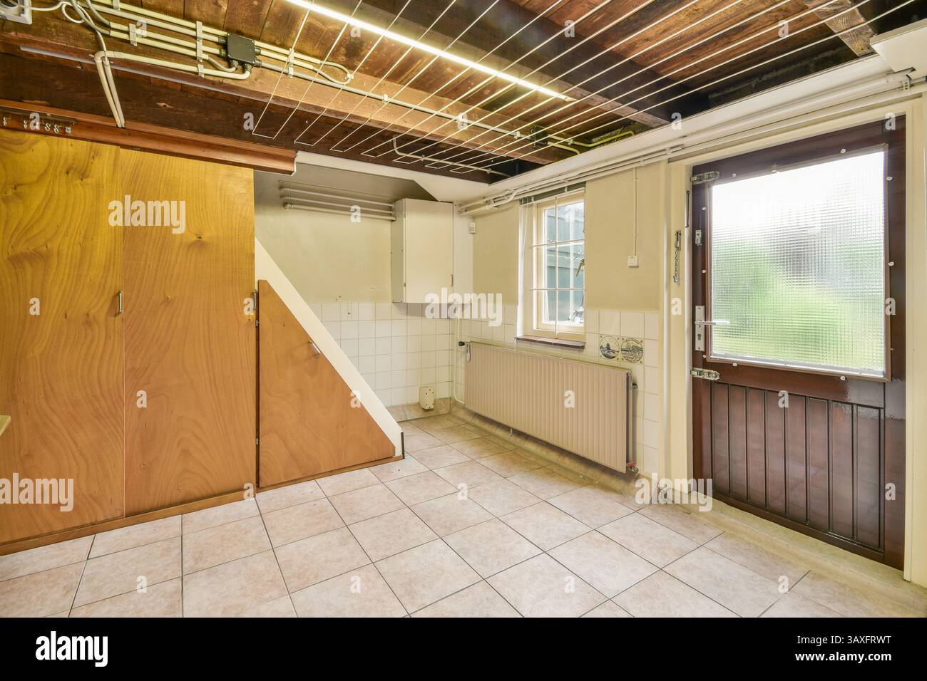 Ein sauberes, modernes Zimmer mit Holzelementen, einem großen Fenster und Wänden in neutralen Farben. Ideal für minimalistisches Design und Funktionalität. Stockfoto