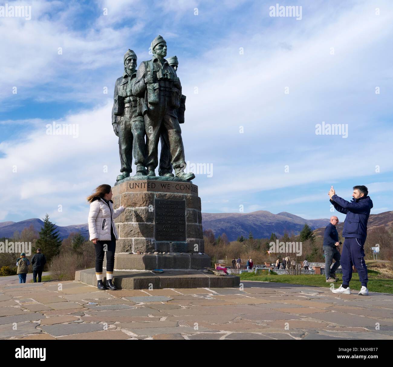 Weibliche Touristen posieren zum Fotografieren neben dem Sockel und den Statuen des Commando Memorial an der Spean Bridge Stockfoto