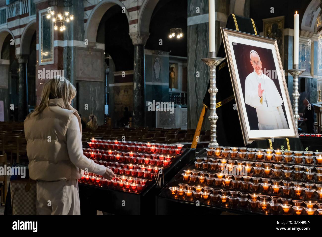 London, Großbritannien. April 2025. Gläubige kommen in der Westminster Cathedral an, um Papst Franziskus zu ehren, wo ein Porträt und Blumenschmuck im Inneren aufgestellt wurden, nachdem sein Tod heute Morgen angekündigt wurde. Der Pontiff starb nach einer Krankheit in den letzten Monaten und machte einen letzten Auftritt, um einen Ostersonntag-Segen auf dem Petersplatz zu halten. Quelle: Eleventh Photography/Alamy Live News Stockfoto