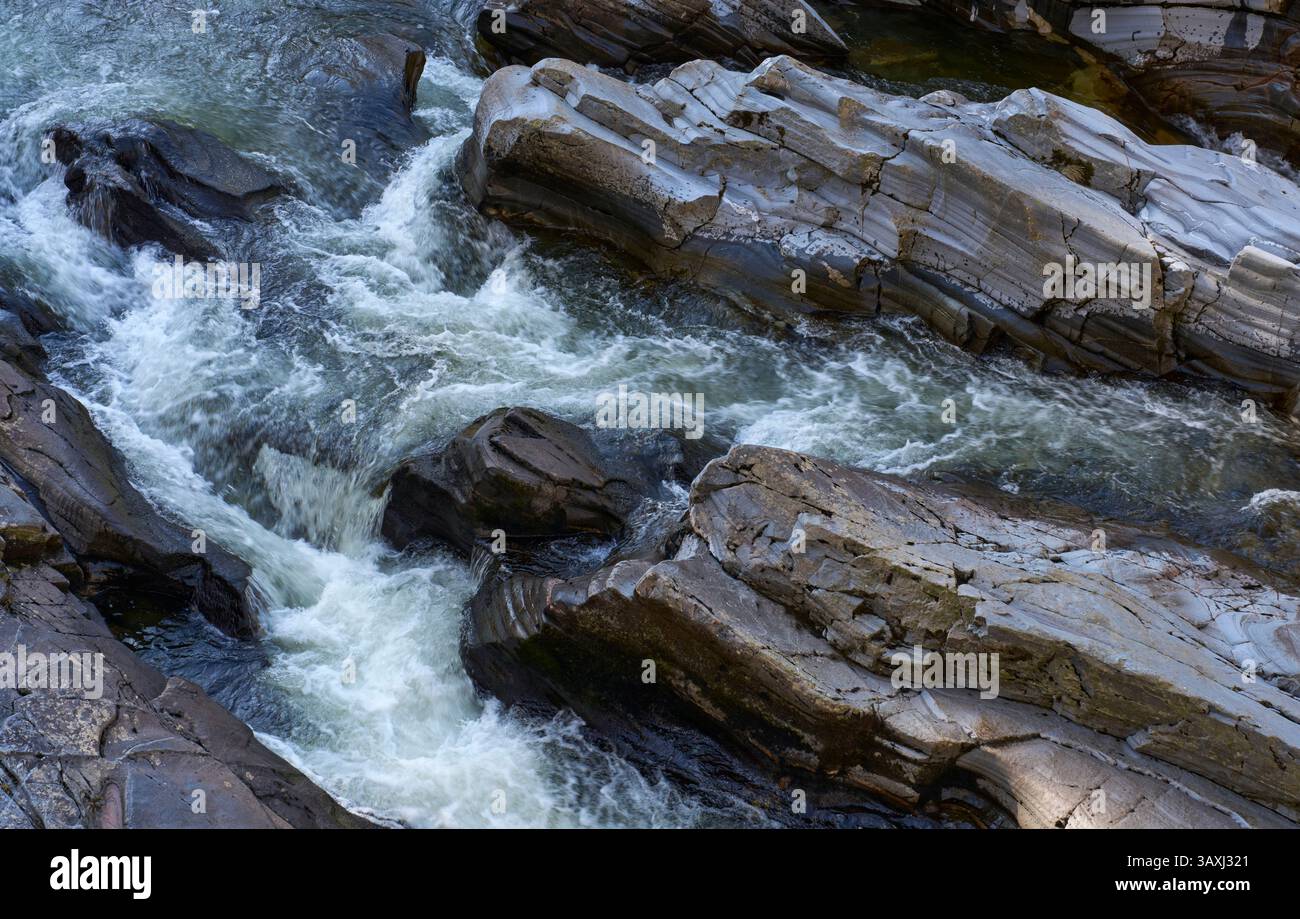 Das Wasser des Flusses Feshie kaskadiert über Felsen bei Feshiebridge bei Kingussie und erzeugt Erosionsmuster in den Schichten Stockfoto