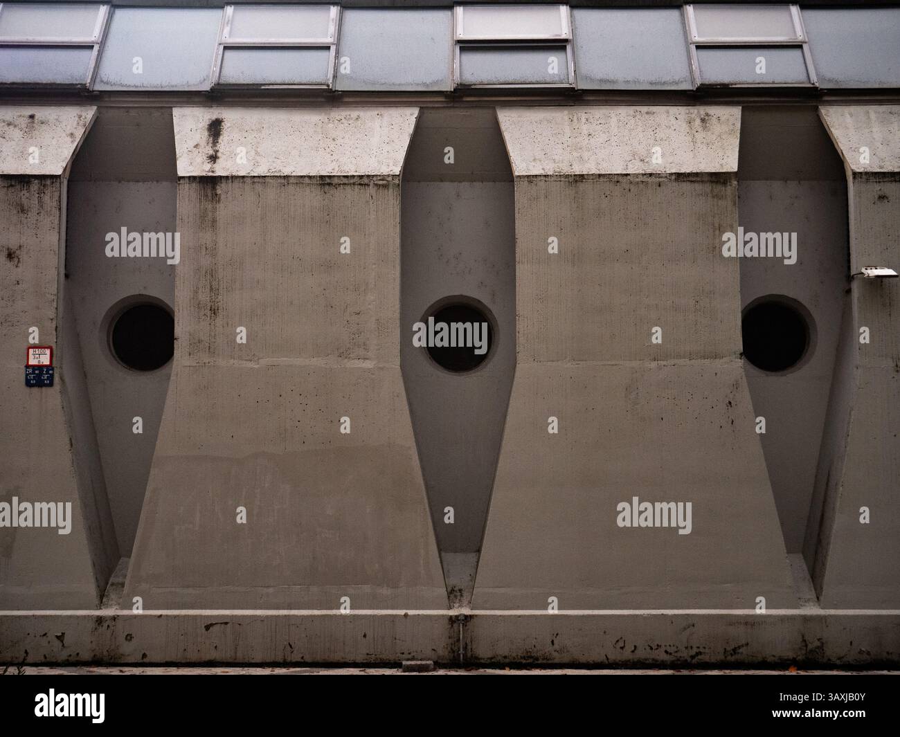 Brutalistischer Betonbau mit kreisförmigen Öffnungen und geometrischen Details unter diffusem Licht, Ljubliana Slowenien Stockfoto