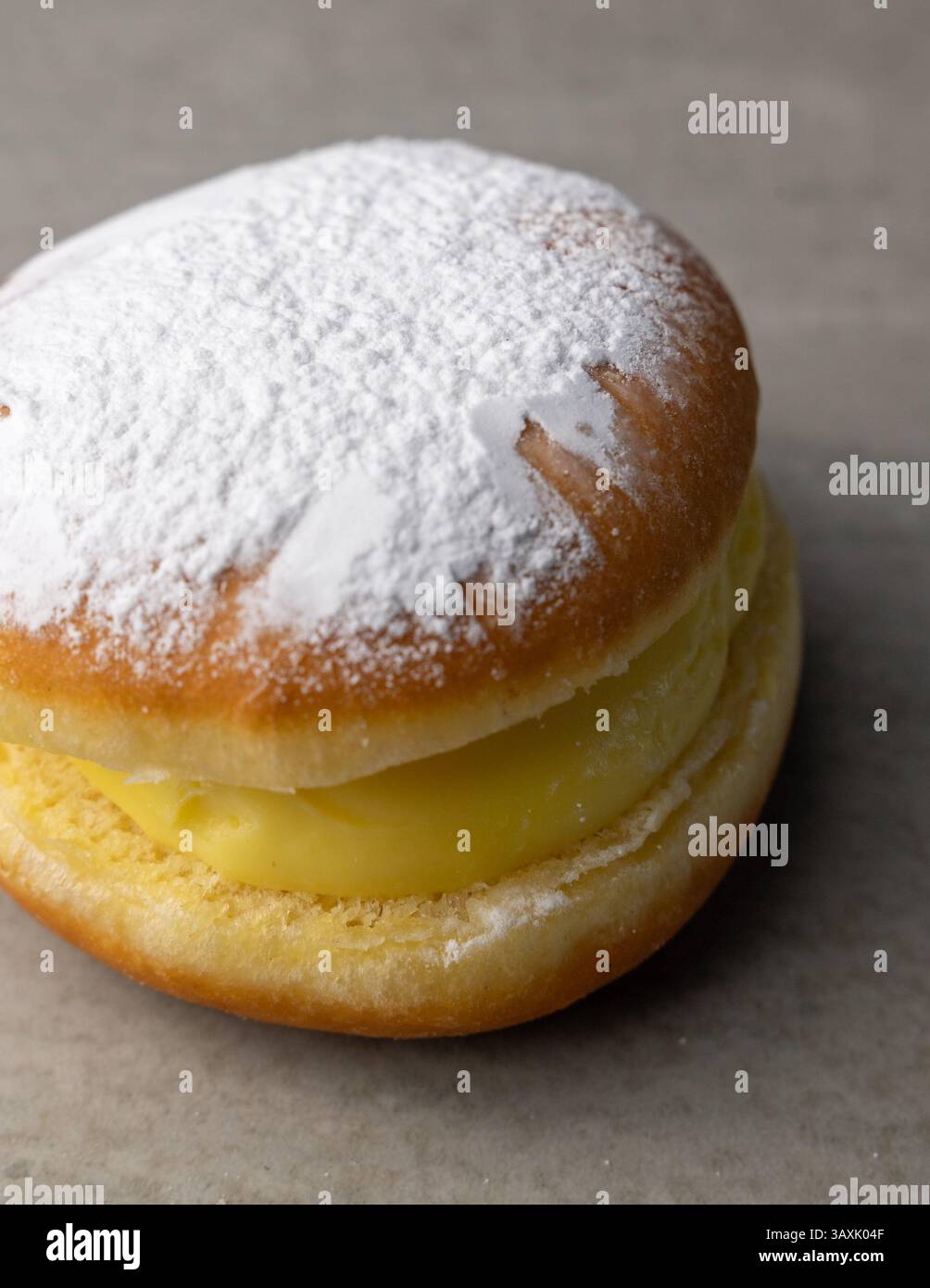 Ein köstlicher, cremegefüllter Donut, mit Puderzucker bestäubt, perfekt für Dessertliebhaber, die süße Leckereien genießen Stockfoto