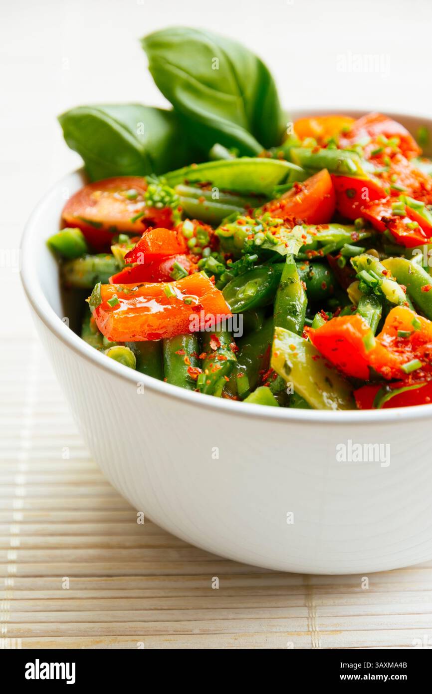 Frühlingssalat mit grünen Bohnen, Zuckererbsenschoten, rotem Paprika und Kirschtomaten. Stockfoto