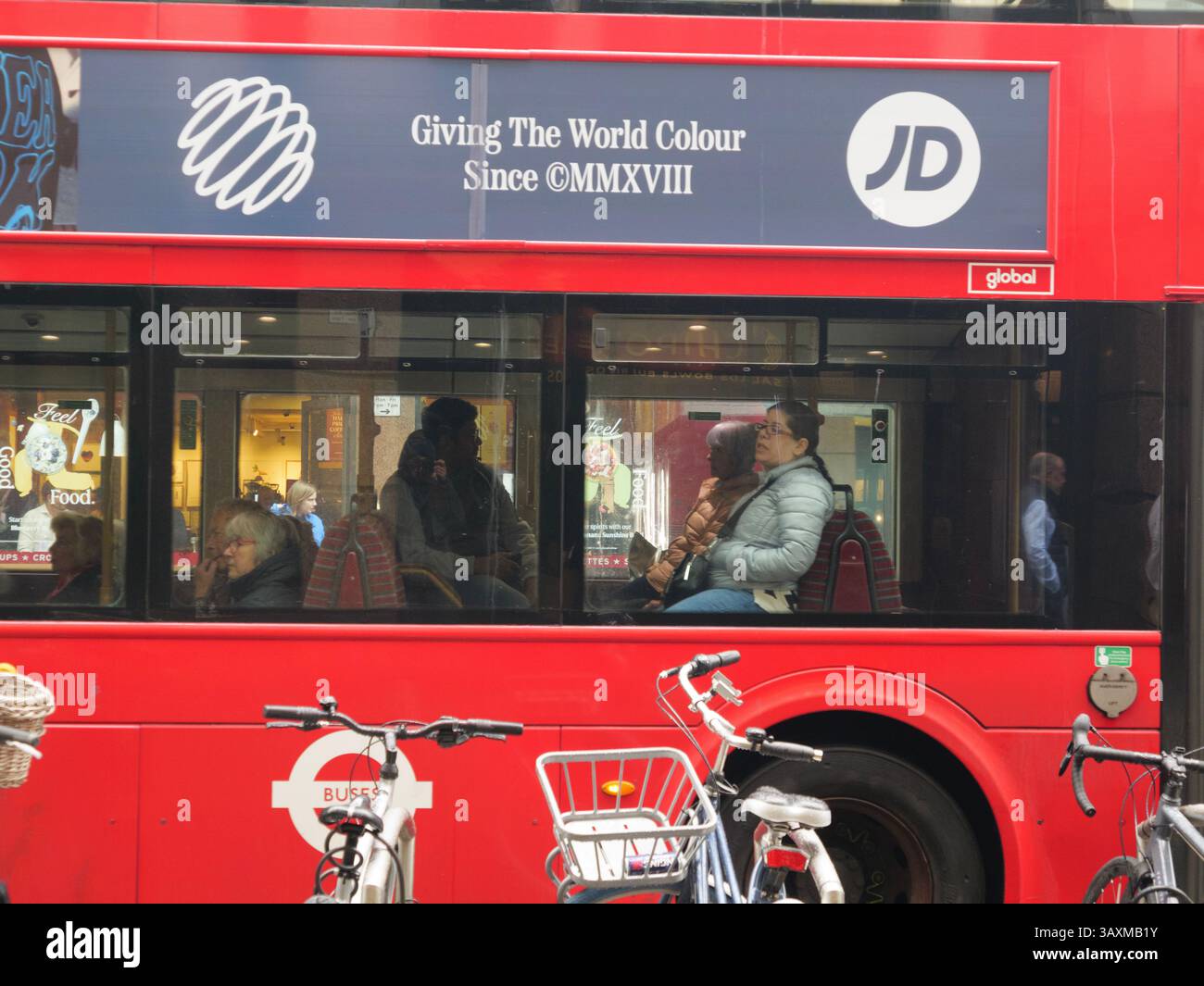Ein klassischer roter Londoner Doppeldeckerbus mit Passagieren fährt durch die Stadt und zeigt eine prominente Werbung von JD Sports auf der Seite über den Global Outdoor Media Space. Stockfoto