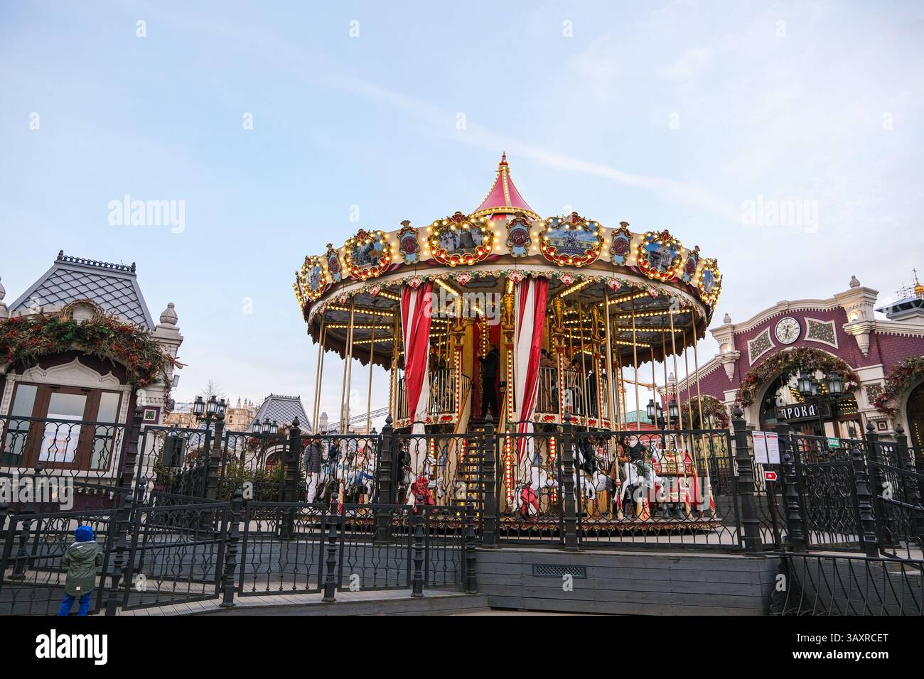 Moskau, Russland, 31.03.2025 Ein Karussell mit einer rot-weißen Spitze ist von einem Zaun umgeben. Das Karussell befindet sich in einem Park und hat eine festliche Atmosphäre Stockfoto