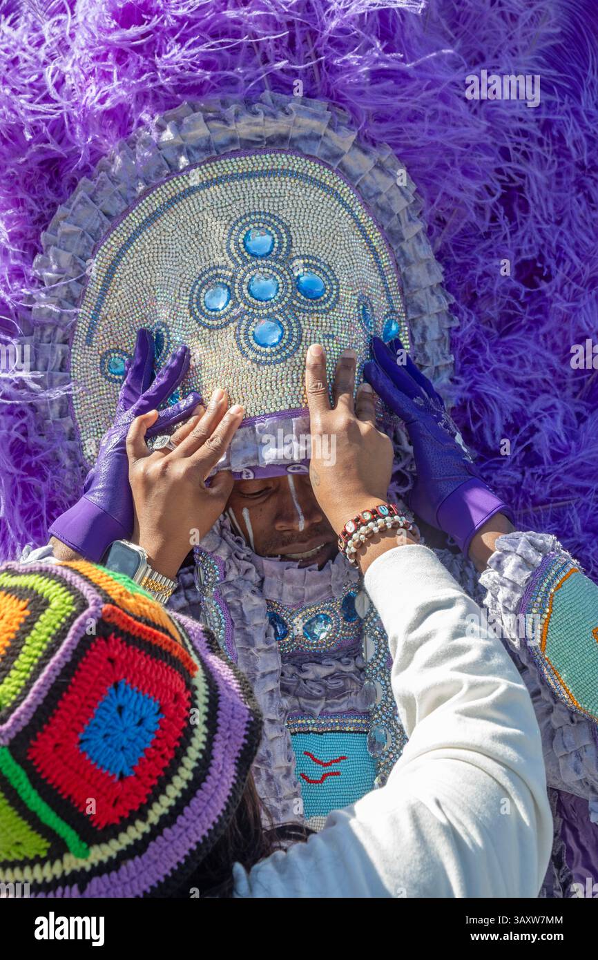 New Orleans, Louisiana – vor der Super Sunday Parade der Mardi Gras Indians wird Einem Mann mit seinem Kostüm geholfen. Afroamerikaner kreieren aufwendige Kostüme Stockfoto