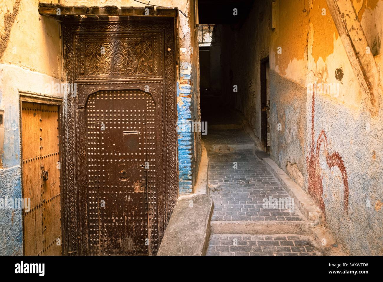 Alte enge Gasse in Fès, Marokko mit geschlossenen Metalltüren und Fenstern Stockfoto